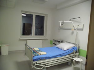 Sala chorych po remoncie - nowe łóżka, białe ściany, szare wykładziny na podłogach.